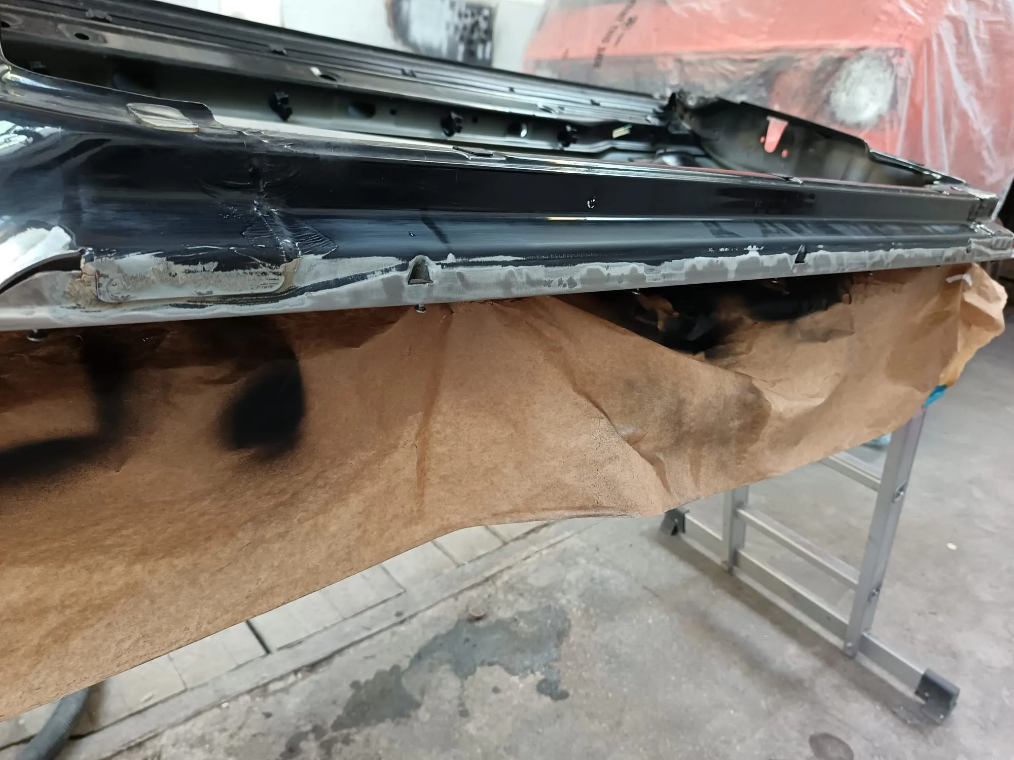 Marginea inferioară a ușii curățată până la metal, chituită și mascată cu hârtie înainte de vopsire