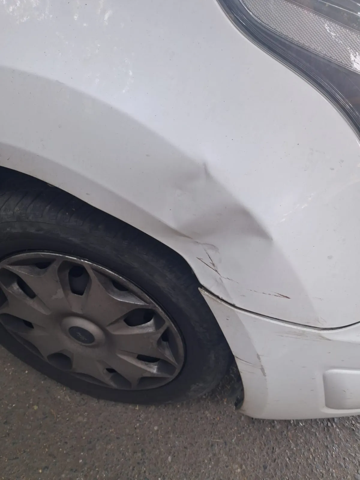 Aripa din față a unui Ford Transit Connect alb, lovită și zgâriată, înainte de reparație